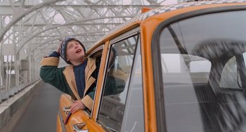Movie still from “Home Alone 2: Lost in New York” (1992), directed by Chris Columbus – A young boy sitting in the driver's seat of an orange taxi cab; Medium shot, Low angle