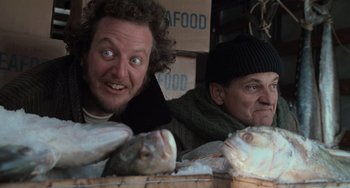 Movie still from “Home Alone 2: Lost in New York” (1992), directed by Chris Columbus – Two men sitting next to each other at a fish market; Close Up shot, Low angle