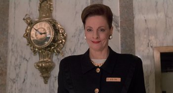 Movie still from “Home Alone 2: Lost in New York” (1992), directed by Chris Columbus – A woman in a black jacket standing in front of a clock; Close Up shot, Low angle