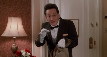 Movie still from “Home Alone 2: Lost in New York” (1992), directed by Chris Columbus – A man in a suit and tie holding a bag; Medium shot, High angle