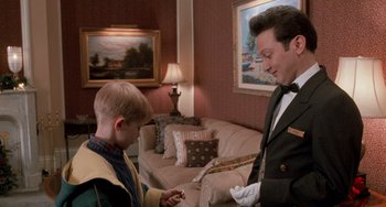 Movie still from “Home Alone 2: Lost in New York” (1992), directed by Chris Columbus – A man in a suit and a boy in a yellow shirt; Medium shot, High angle