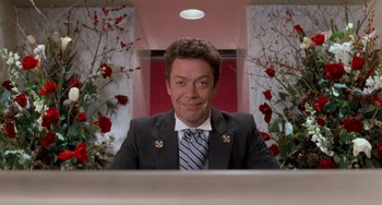 Movie still from “Home Alone 2: Lost in New York” (1992), directed by Chris Columbus – A man sitting at a desk in front of a mirror; Medium shot, Low angle