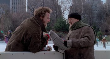 Movie still from “Home Alone 2: Lost in New York” (1992), directed by Chris Columbus – Two people are looking at a newspaper outside; Medium shot, Low angle