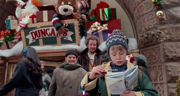 Movie still from “Home Alone 2: Lost in New York” (1992), directed by Chris Columbus – A group of people standing in front of christmas decorations; Medium shot, Over the shoulder angle