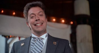 Movie still from “Home Alone 2: Lost in New York” (1992), directed by Chris Columbus – A man in a suit and tie smiling for the camera; Close Up shot, Low angle