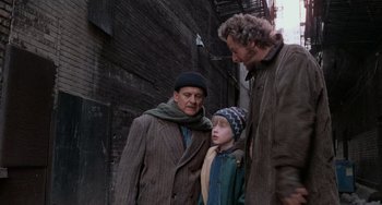 Movie still from “Home Alone 2: Lost in New York” (1992), directed by Chris Columbus – Three men standing next to each other on a street; Medium shot, Over the shoulder angle