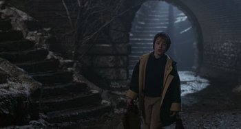 Movie still from “Home Alone 2: Lost in New York” (1992), directed by Chris Columbus – A young boy walking down the stairs in a dark place; Medium shot, High angle