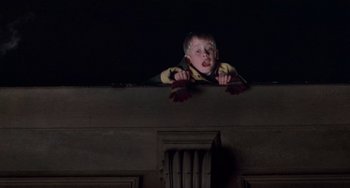 Movie still from “Home Alone 2: Lost in New York” (1992), directed by Chris Columbus – A young boy is sitting on the ledge of a building; Medium shot, Low angle