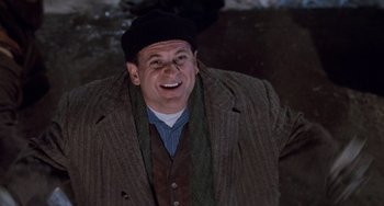 Movie still from “Home Alone 2: Lost in New York” (1992), directed by Chris Columbus – A man wearing a hat and a jacket smiling for the camera; Medium shot, Low angle