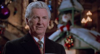 Movie still from “Home Alone 2: Lost in New York” (1992), directed by Chris Columbus – An older man wearing a suit and tie in front of a christmas tree; Close Up shot, Over the shoulder angle