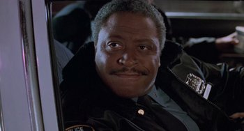 Movie still from “Home Alone 2: Lost in New York” (1992), directed by Chris Columbus – A police officer sitting in the back of a car; Close Up shot, Low angle