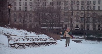 Movie still from “Home Alone 2: Lost in New York” (1992), directed by Chris Columbus – A boy is running in the snow near a park bench; Extreme Wide shot, High angle