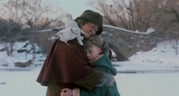 Movie still from “Home Alone 2: Lost in New York” (1992), directed by Chris Columbus – Two children are hugging in the snow with a bird on their shoulder; Medium shot, Low angle