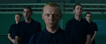 Movie still from “Hot Fuzz” (2007), directed by Edgar Wright – A man in a black shirt and two other men; Medium shot, Low angle