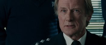 Movie still from “Hot Fuzz” (2007), directed by Edgar Wright – A person wearing a suit and tie; Close Up shot, Over the shoulder angle
