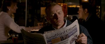 Movie still from “Hot Fuzz” (2007), directed by Edgar Wright – A man is reading a newspaper in a room; Close Up shot, Over the shoulder angle