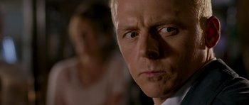 Movie still from “Hot Fuzz” (2007), directed by Edgar Wright – A man's face with a woman in the background; Close Up shot, Over the shoulder angle