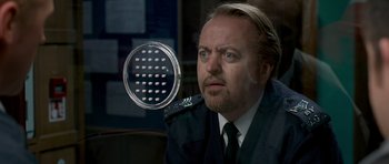 Movie still from “Hot Fuzz” (2007), directed by Edgar Wright – A person wearing a suit and tie; Close Up shot, Over the shoulder angle