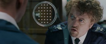 Movie still from “Hot Fuzz” (2007), directed by Edgar Wright – A person in a uniform looking out of a window; Close Up shot, Over the shoulder angle
