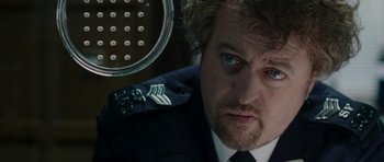 Movie still from “Hot Fuzz” (2007), directed by Edgar Wright – A person wearing a suit and tie; Close Up shot, Over the shoulder angle