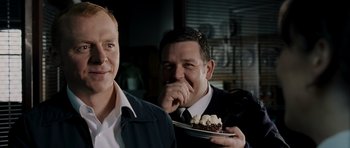 Movie still from “Hot Fuzz” (2007), directed by Edgar Wright – Two men in business suits are eating a dessert; Medium shot, Over the shoulder angle