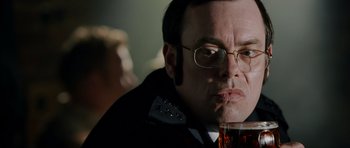 Movie still from “Hot Fuzz” (2007), directed by Edgar Wright – A man with glasses is holding a glass of beer; Close Up shot, Over the shoulder angle