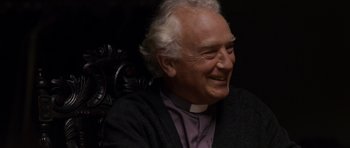 Movie still from “Hot Fuzz” (2007), directed by Edgar Wright – An older man wearing a priest's collar and smiling; Close Up shot, High angle