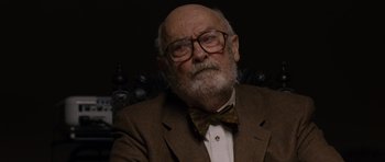 Movie still from “Hot Fuzz” (2007), directed by Edgar Wright – An old man with a beard wearing glasses and a bow tie; Close Up shot, Over the shoulder angle
