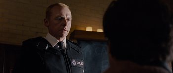 Movie still from “Hot Fuzz” (2007), directed by Edgar Wright – A man in a police uniform talking to someone; Close Up shot, Over the shoulder angle