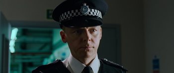 Movie still from “Hot Fuzz” (2007), directed by Edgar Wright – A man in a police uniform is looking at the camera; Close Up shot, Low angle