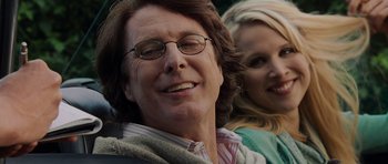 Movie still from “Hot Fuzz” (2007), directed by Edgar Wright – A person wearing glasses with a woman in the background; Close Up shot, Low angle