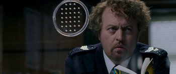 Movie still from “Hot Fuzz” (2007), directed by Edgar Wright – A person wearing a suit and tie; Close Up shot, Over the shoulder angle