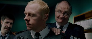 Movie still from “Hot Fuzz” (2007), directed by Edgar Wright – A man with a bald head and a man with a bald head; Close Up shot, Over the shoulder angle