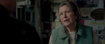 Movie still from “Hot Fuzz” (2007), directed by Edgar Wright – An older woman wearing a green vest looking off into the distance; Close Up shot, Over the shoulder angle