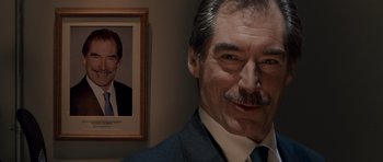 Movie still from “Hot Fuzz” (2007), directed by Edgar Wright – A man in a suit standing next to a picture of himself; Close Up shot, Over the shoulder angle
