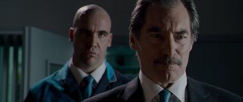 Movie still from “Hot Fuzz” (2007), directed by Edgar Wright – A man in a suit and tie standing next to another man in a suit and tie; Close Up shot, Over the shoulder angle