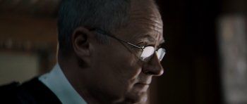 An older man wearing glasses looking off into the distance