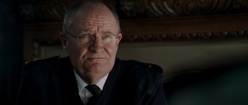 Movie still from “Hot Fuzz” (2007), directed by Edgar Wright – An older man wearing glasses and a jacket; Close Up shot, Over the shoulder angle