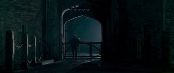 Movie still from “Hot Fuzz” (2007), directed by Edgar Wright – A man standing on a bridge at night; Extreme Wide shot, Low angle