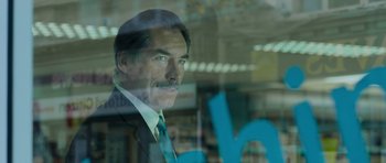 Movie still from “Hot Fuzz” (2007), directed by Edgar Wright – A person wearing a suit and tie; Close Up shot, Over the shoulder angle