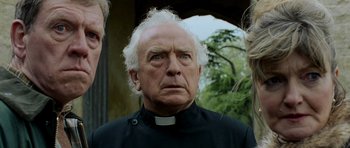 Movie still from “Hot Fuzz” (2007), directed by Edgar Wright – An older man wearing a priest's collar; Close Up shot, Low angle