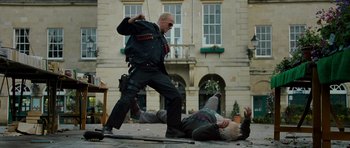 Movie still from “Hot Fuzz” (2007), directed by Edgar Wright – A man in black shirt and sunglasses standing over another man in black shirt; Wide shot, Low angle