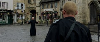 Movie still from “Hot Fuzz” (2007), directed by Edgar Wright – A man in a priest's outfit is standing in front of another man; Wide shot, Over the shoulder angle