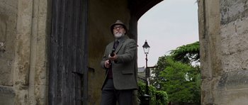 Movie still from “Hot Fuzz” (2007), directed by Edgar Wright – An older man in a suit and hat holding a gun; Medium shot, Low angle