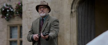 Movie still from “Hot Fuzz” (2007), directed by Edgar Wright – An older man in a suit and hat holding a cell phone; Medium shot, Low angle