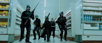 Movie still from “Hot Fuzz” (2007), directed by Edgar Wright – A group of men in black suits and helmets holding guns; Wide shot, Low angle
