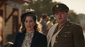 Movie still from “A League of Their Own” (2022), created by Abbi Jacobson – A man and a woman dressed up in military uniforms; Medium shot, Over the shoulder angle