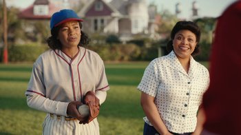 Movie still from “A League of Their Own” (2022), created by Abbi Jacobson – Two women standing next to each other on a baseball field; Medium shot, Over the shoulder angle