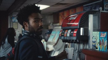 Movie still from “Atlanta” (2016), created by Donald Glover – A man is drinking a beverage from a machine; Close Up shot, Over the shoulder angle