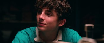 Movie still from “Hot Summer Nights” (2017), directed by Elijah Bynum – A young man in a green shirt looks to his left; Close Up shot, Over the shoulder angle